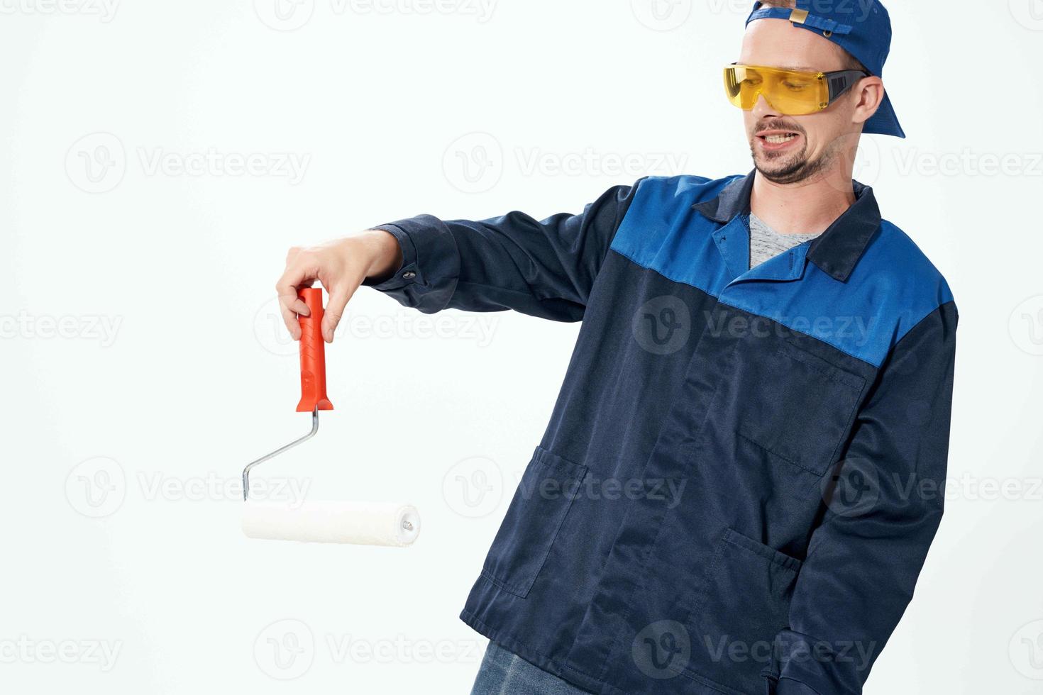a man in a working uniform a roller for painting walls in his hands decoration repair photo