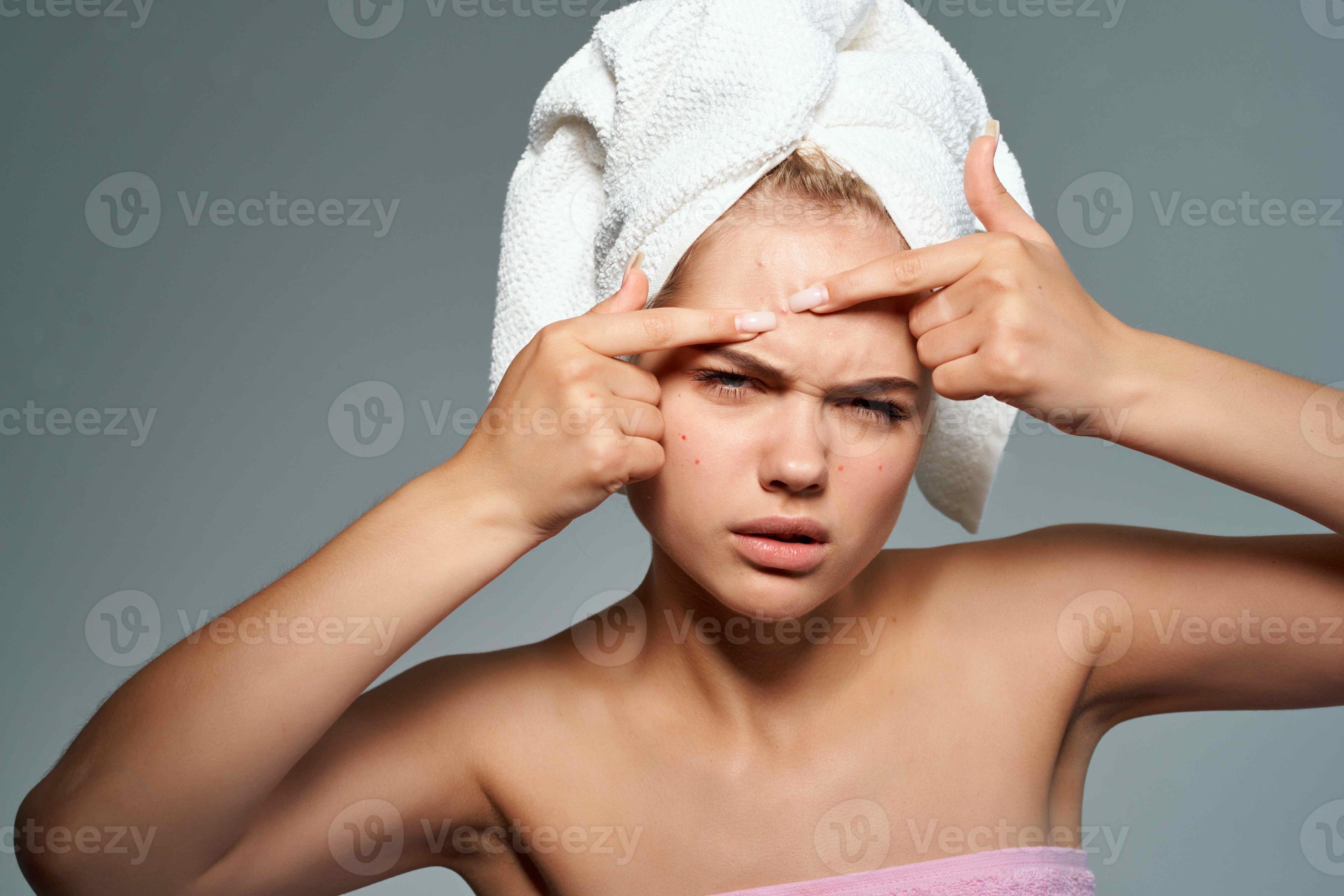 pretty woman with bare shoulders squeeze pimples on her face skin