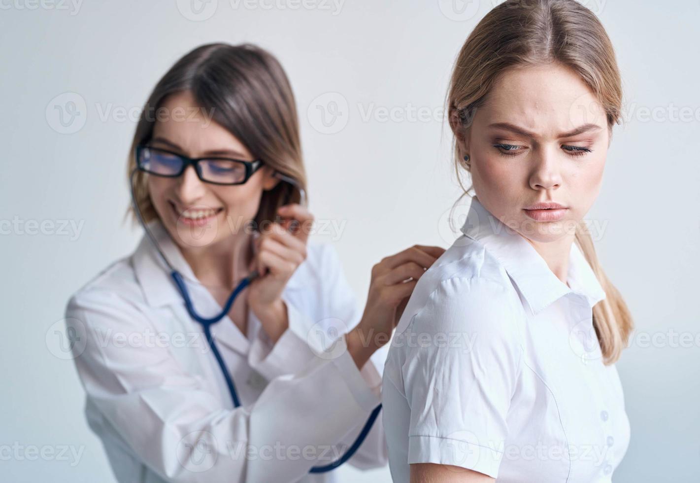 the patient turned her back to the doctor in a medical gown with a stethoscope photo