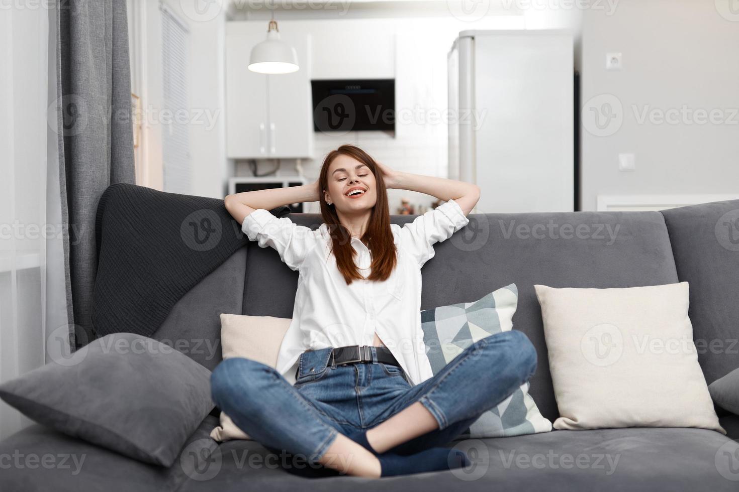 woman with closed eyes sitting on the couch threw back her head at home photo