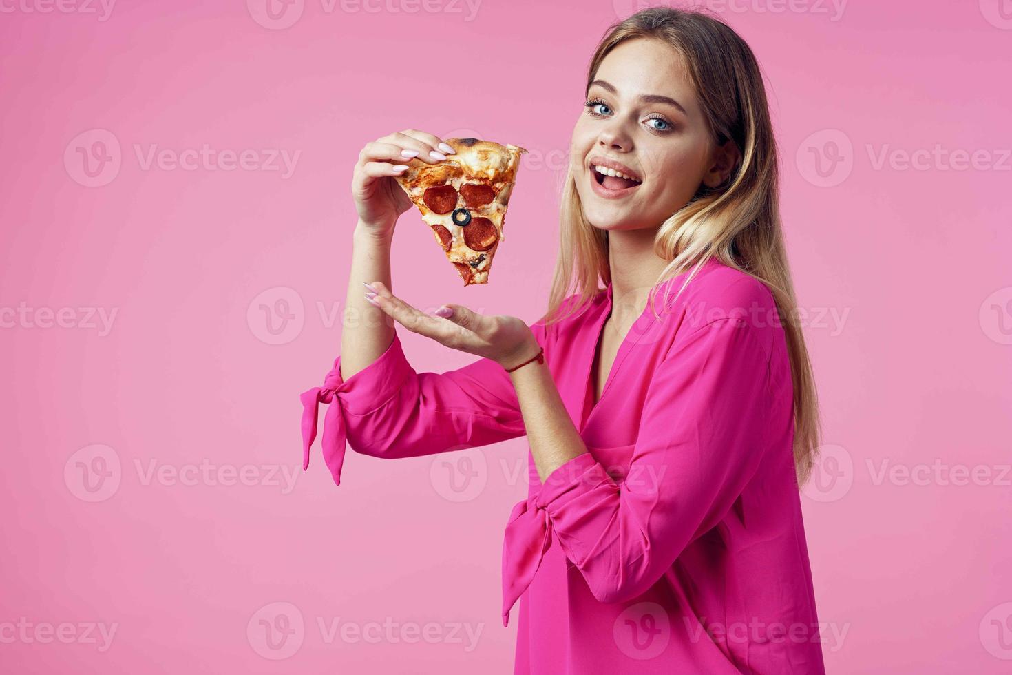 cheerful blonde with pizza in her hands junk food snack pink background photo