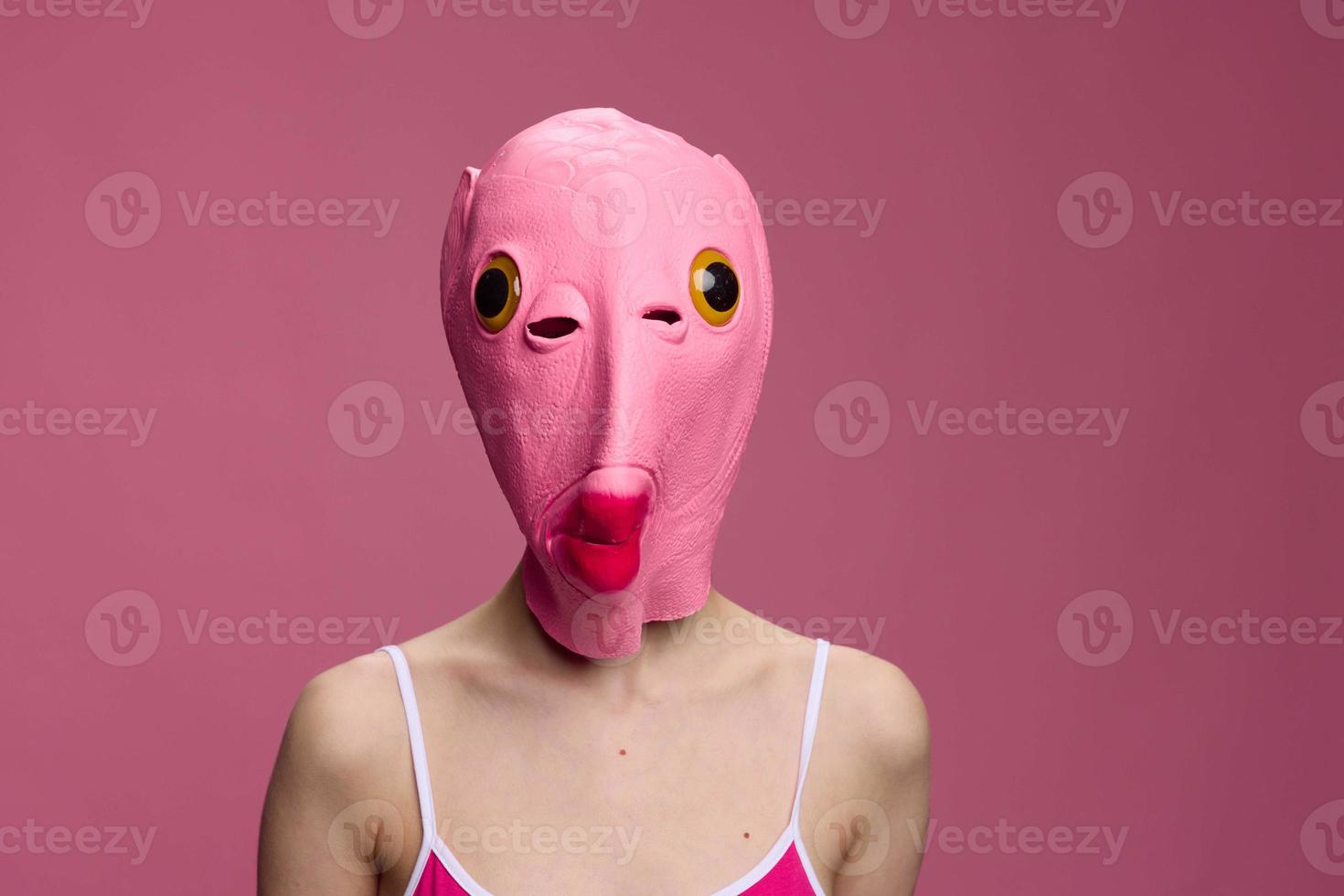 Conceptual art photo of a sexy woman in a fish mask for Halloween on a pink background