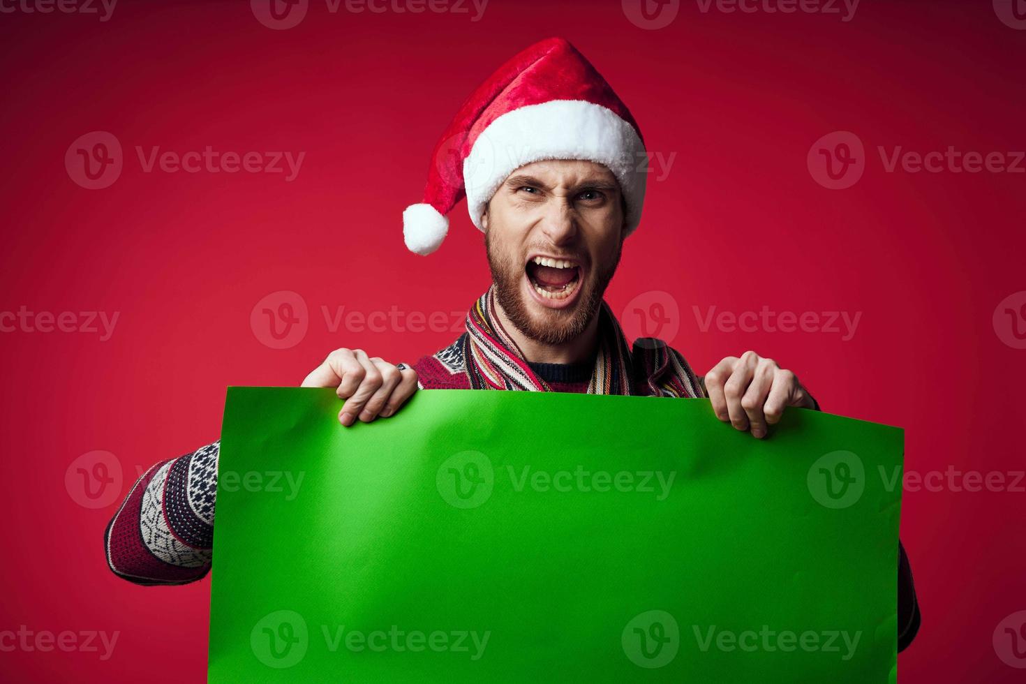 handsome man in a christmas hat with green mockup red background photo