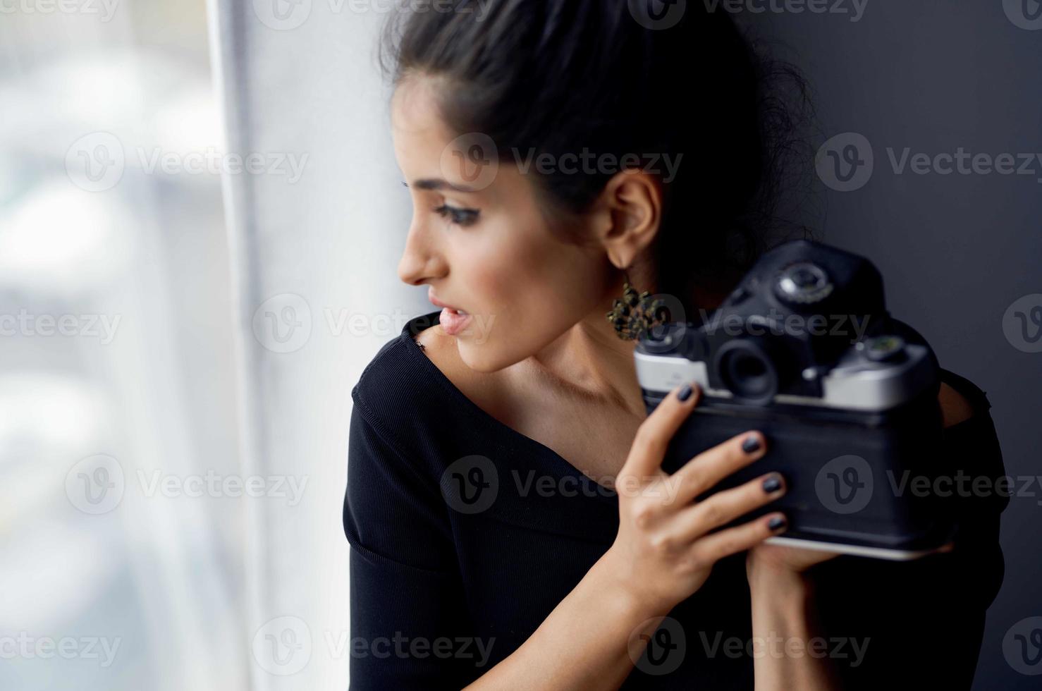 pretty woman holding a camera near the window decoration fashion lifestyle studio photo