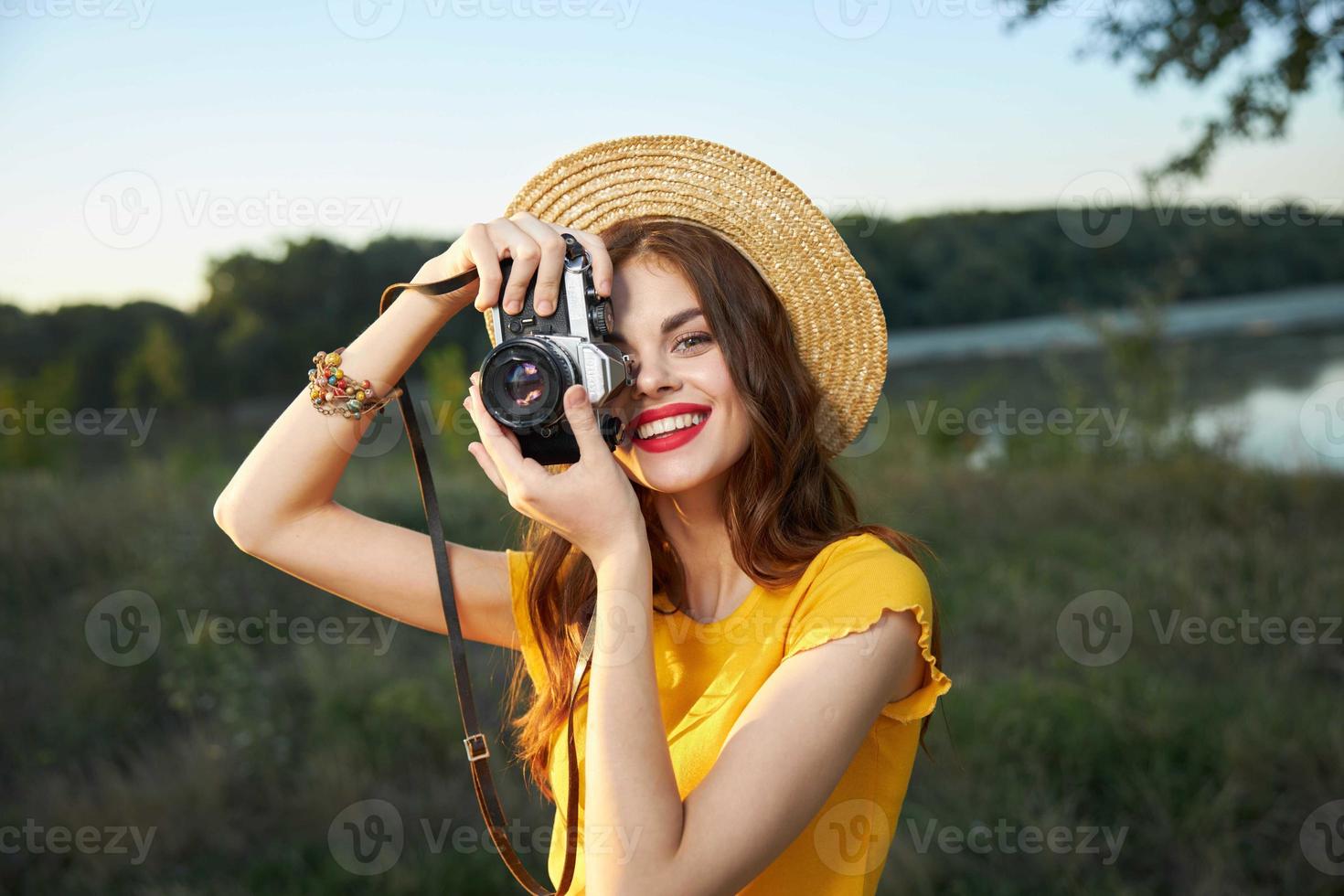 sonriente mujer mira dentro el cámara lente rojo labios amarillo camiseta naturaleza foto