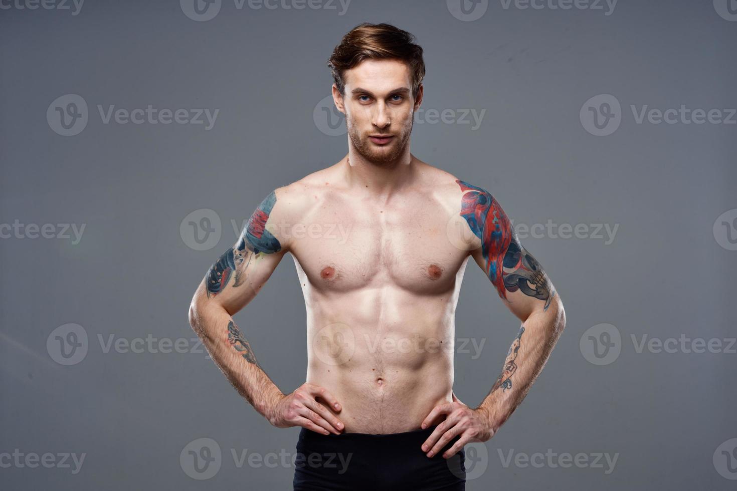 sporty man pumped up press acting out on his arms cropped view gray background photo