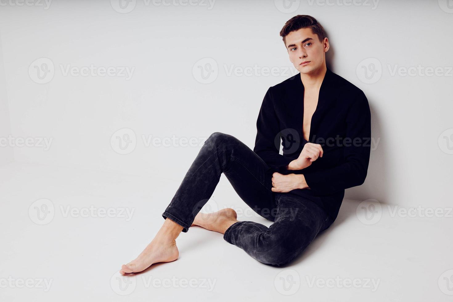 A handsome man is sitting on the floor in a black modern style jacket photo