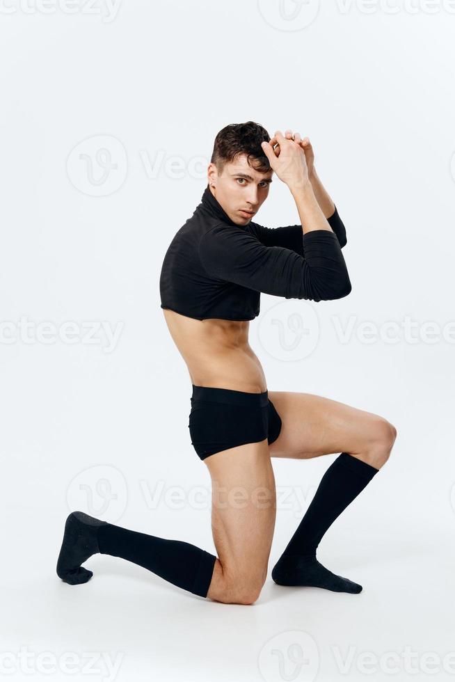 a man of an athletic physique kneels in shorts and socks on a light background photo