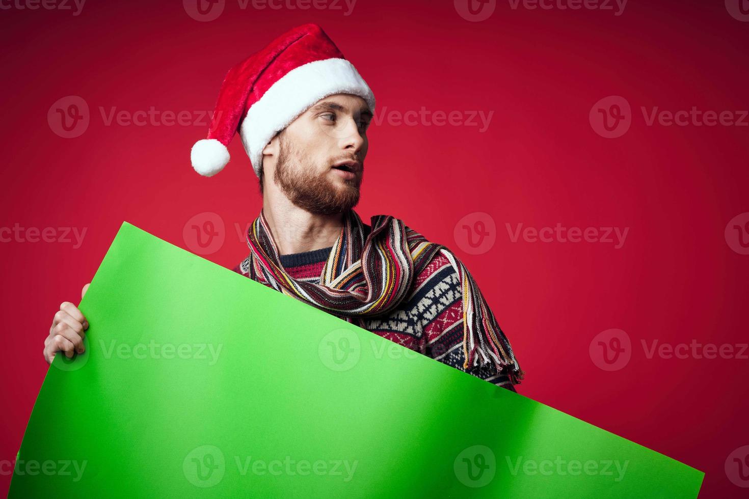 Cheerful man in a christmas hat with green mockup red background photo