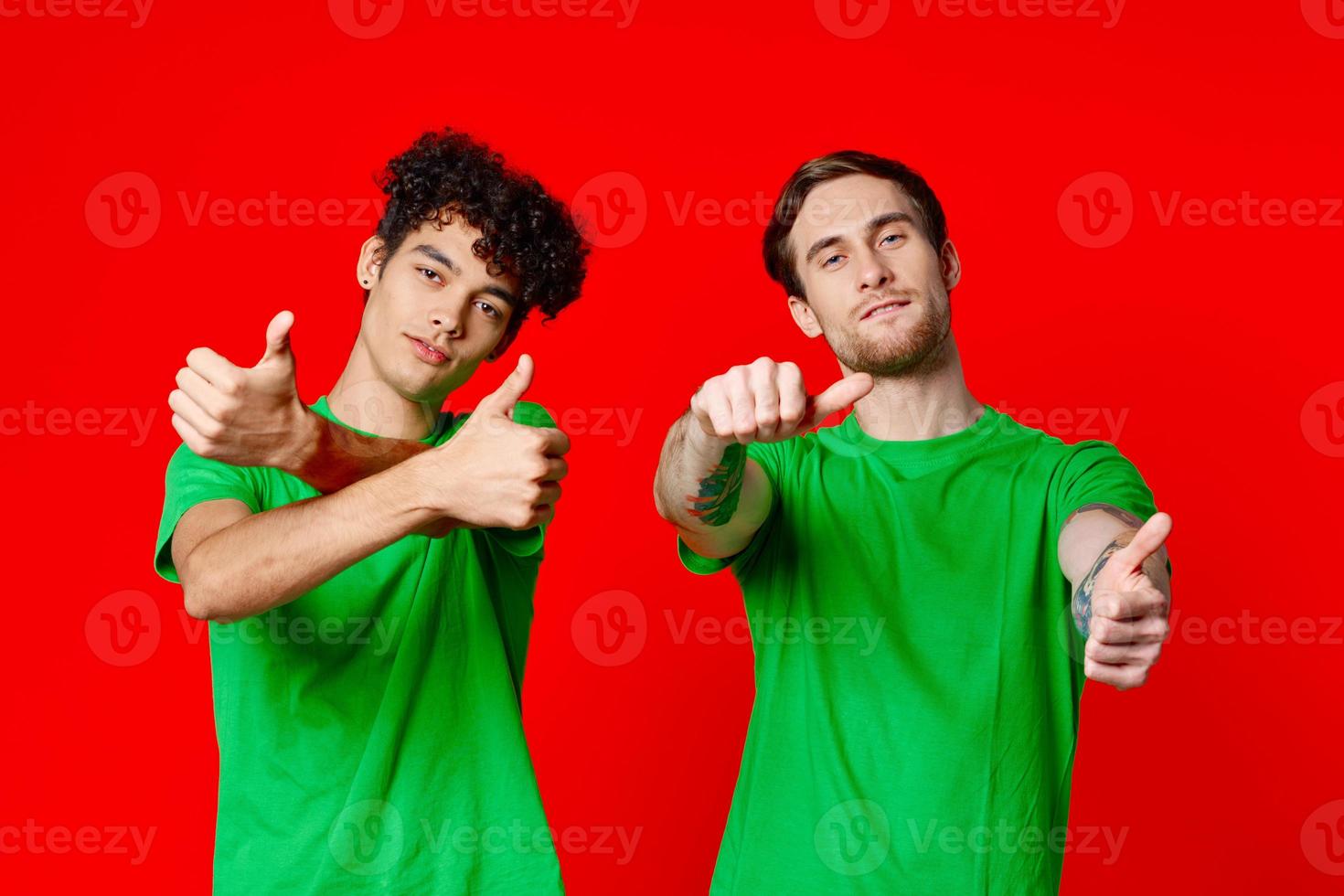Cheerful friends in green t-shirts gesturing with hands emotions red background photo