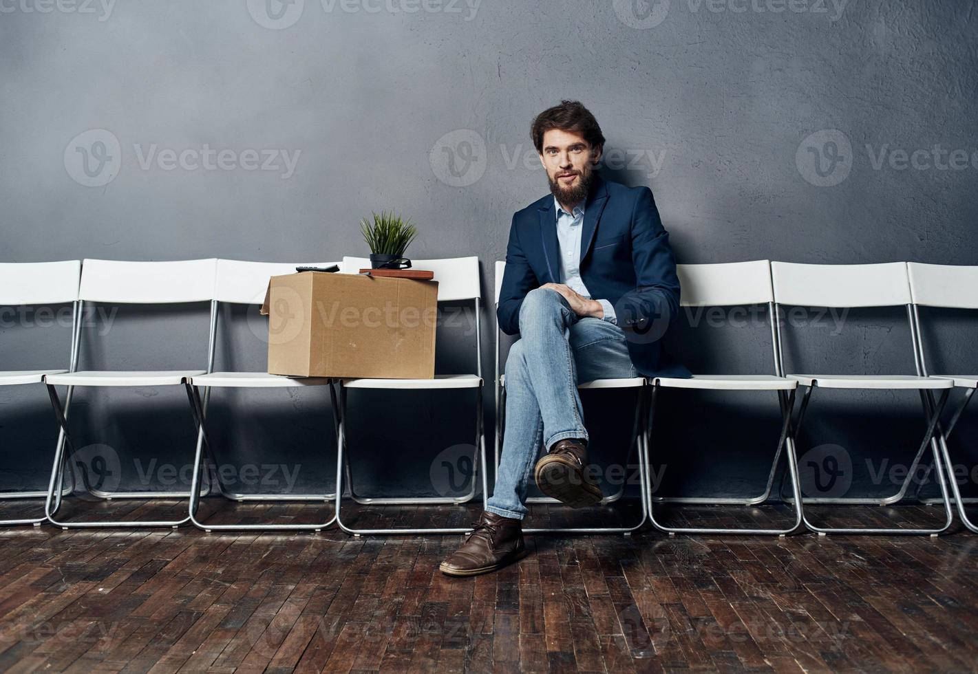 A man with things in a box sits on a chair waiting for discontent photo
