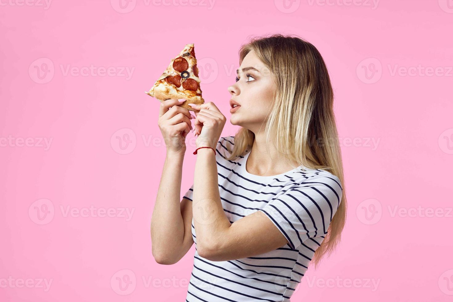 woman in striped t-shirt with pizza in hands fast food snack pink background photo