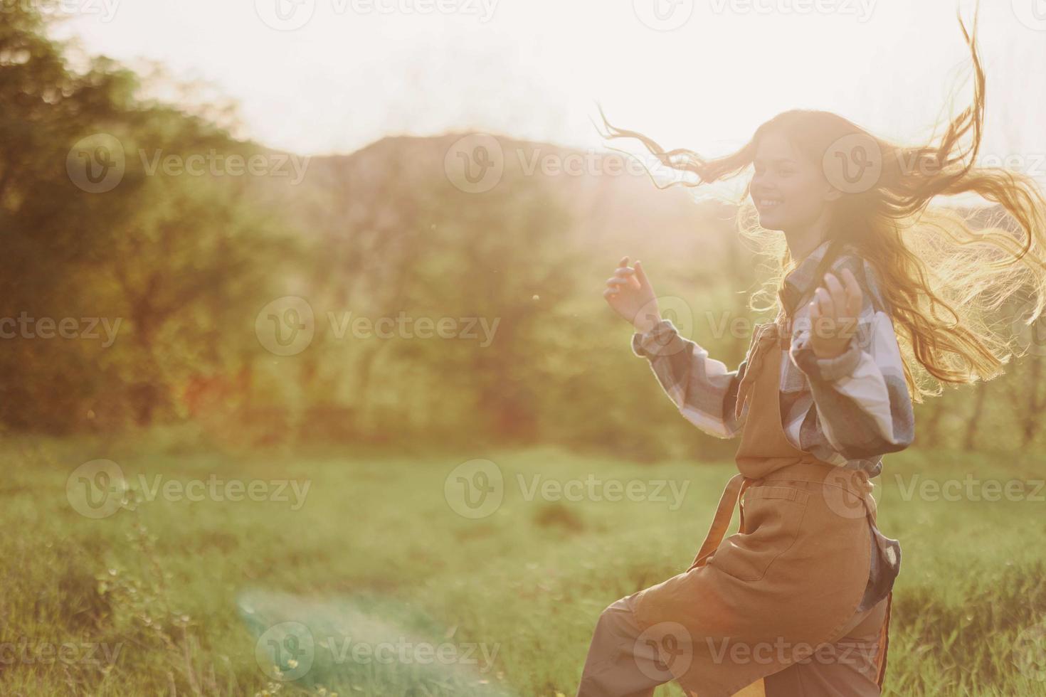 A woman running through a field on a summer day with long flowing hair in the rays of the setting sun. The concept of freedom and harmony with nature photo