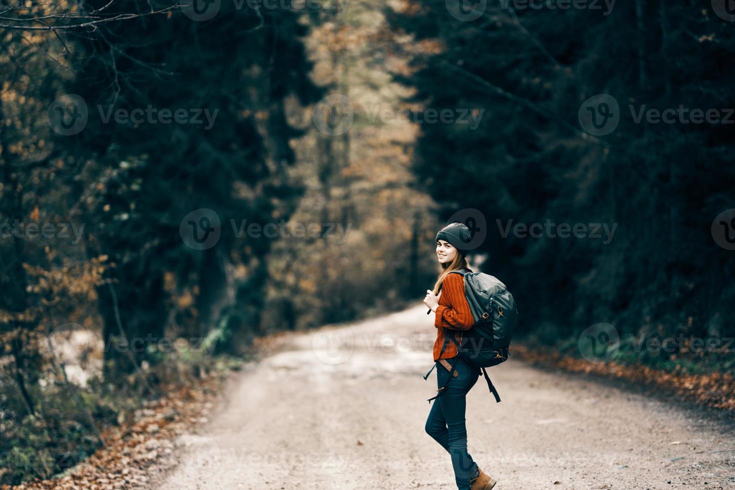 woman with backpack on the road in the forest in autumn landscape tall trees model photo