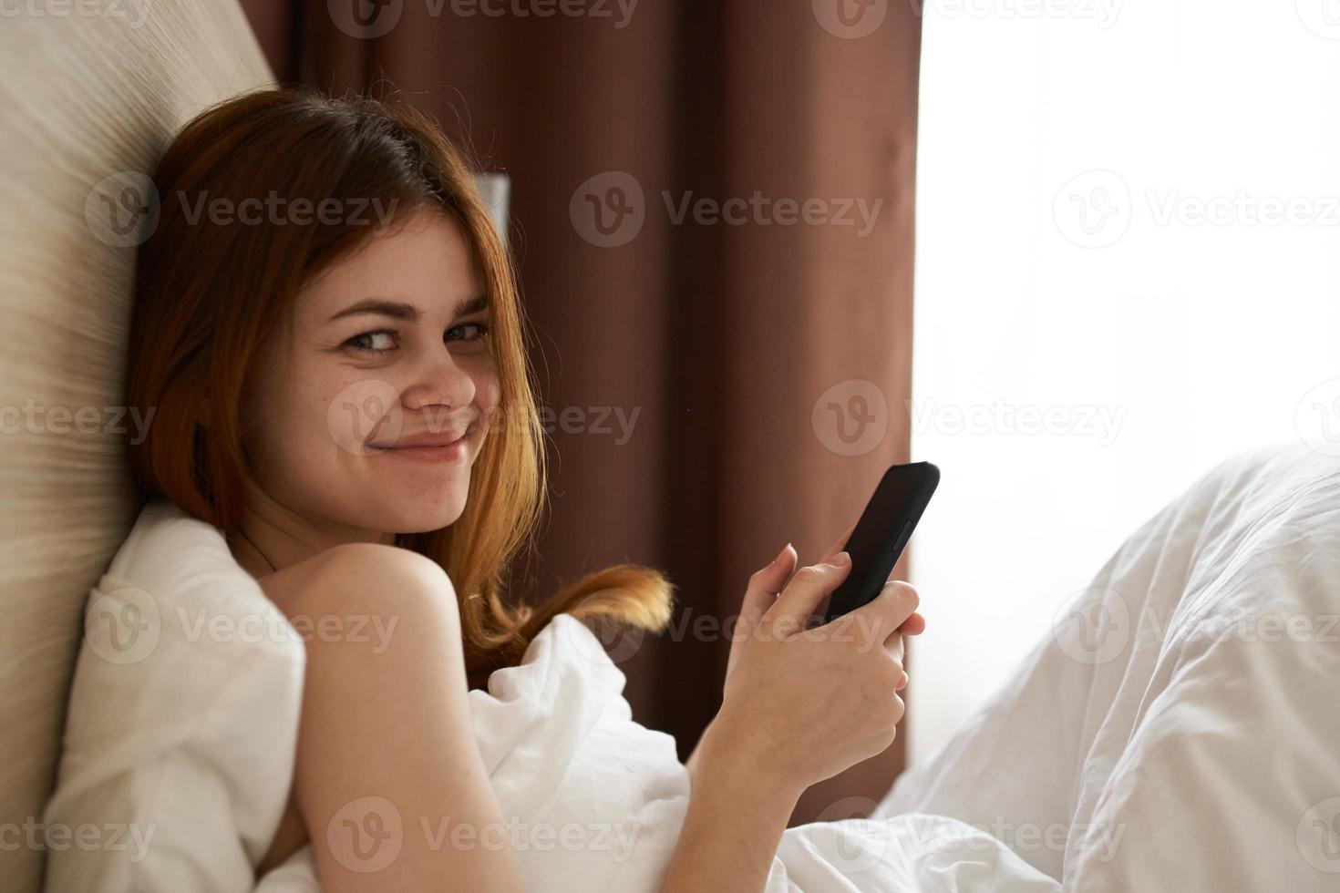 woman in bed under the covers near the window cropped view 22076621