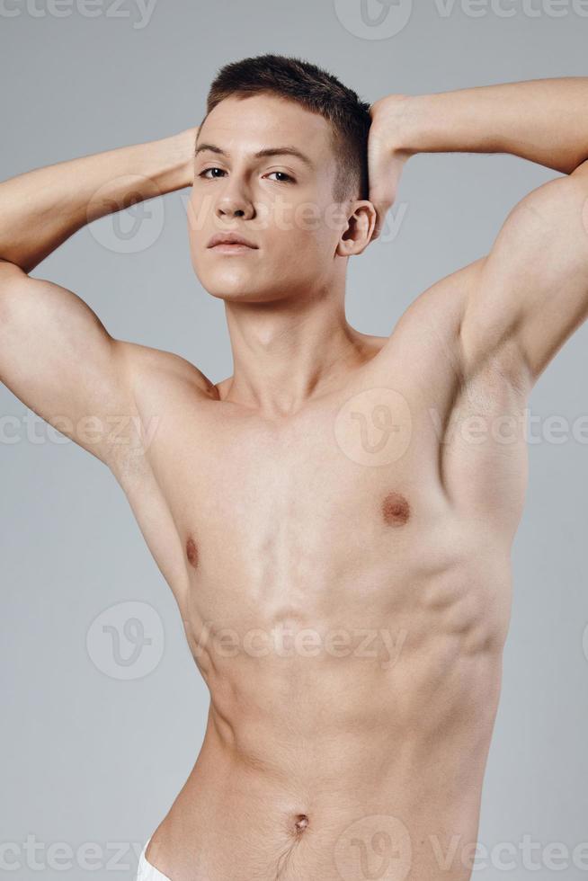 handsome man with pumped up muscles holds his hands behind his head cropped view Copy Space photo