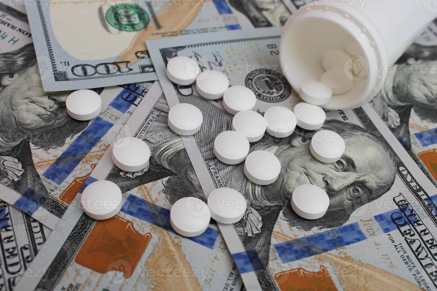 Pills spilling from container on the background of dollars photo