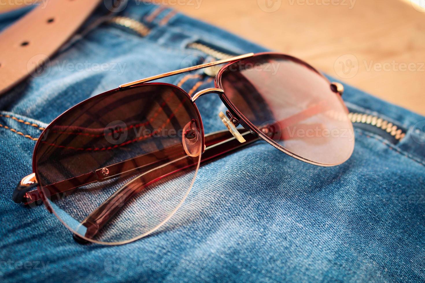 Sunglasses on jeans background. Toned image. photo