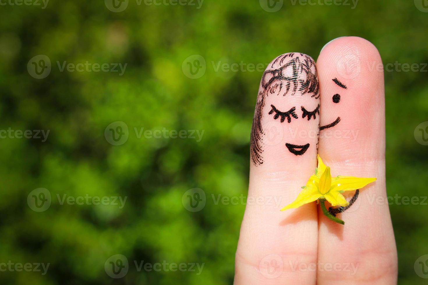 cara pintado en dedos. hombre es dando flores a un mujer. foto