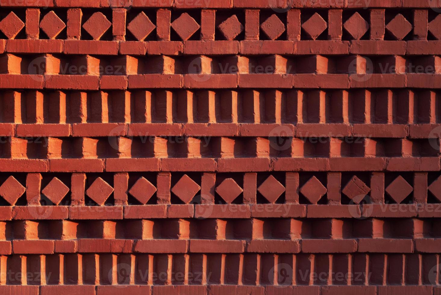 Red brick wall with ornamental pattern in shadow and light gradient photo