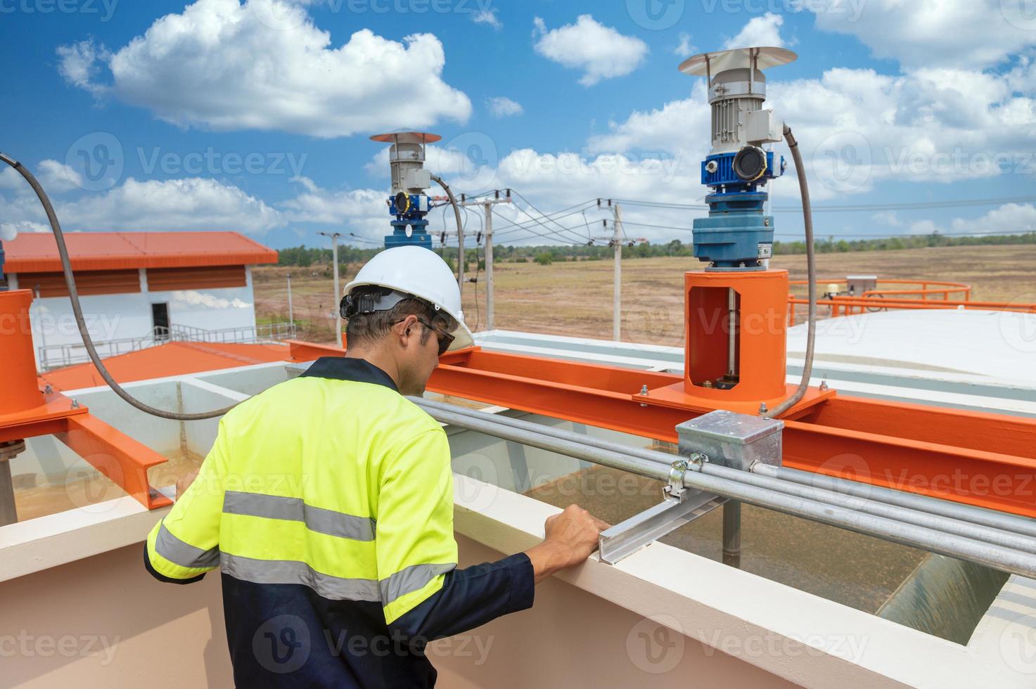 Industrial plumbing, overworked engineer wearing protective clothing and helmet on head while standing in industrial plant inspecting water supply system photo