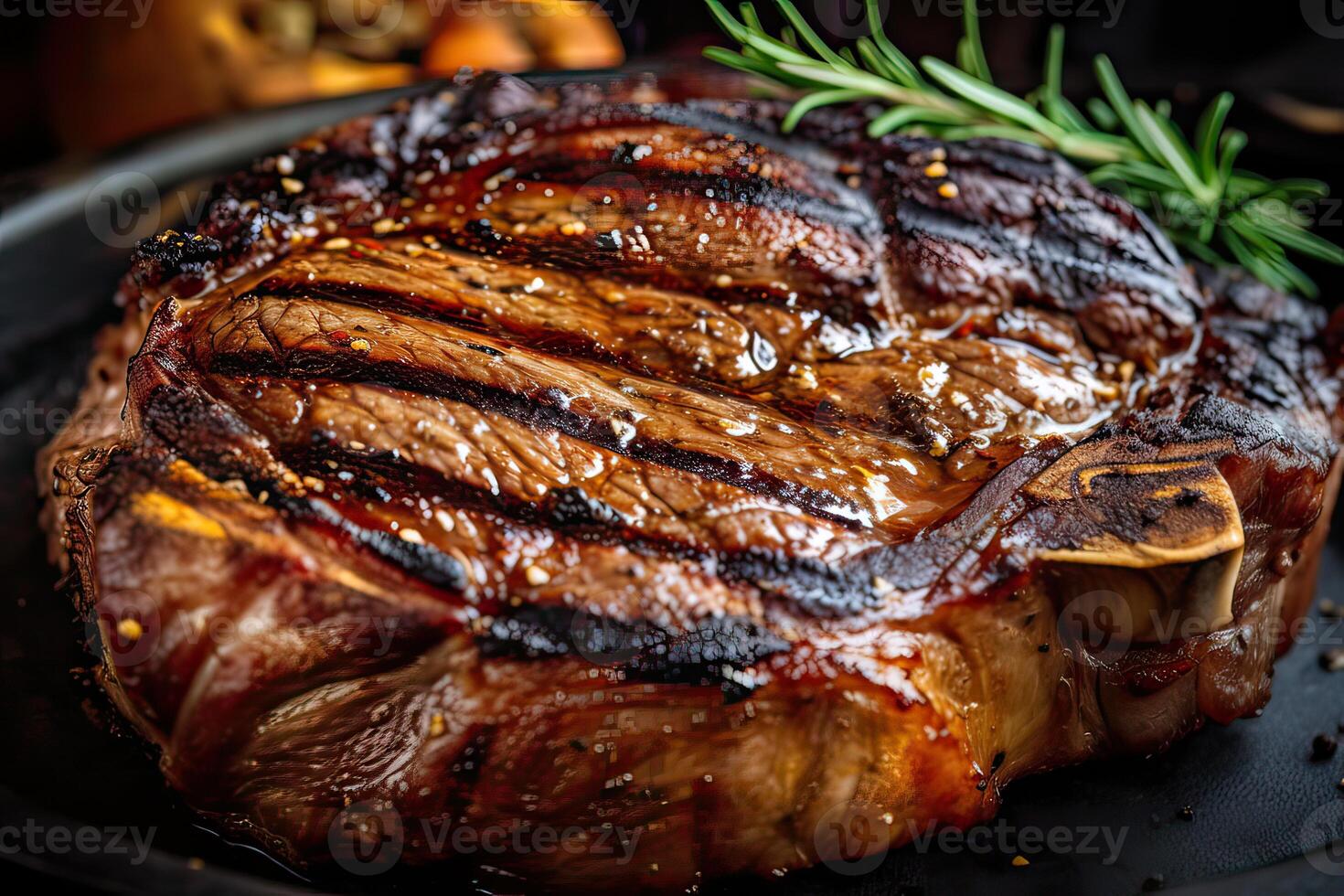 Grilled ribeye beef steak served on wooden board with rosemary, grilled garlic, fork and knife on wooden table. . photo