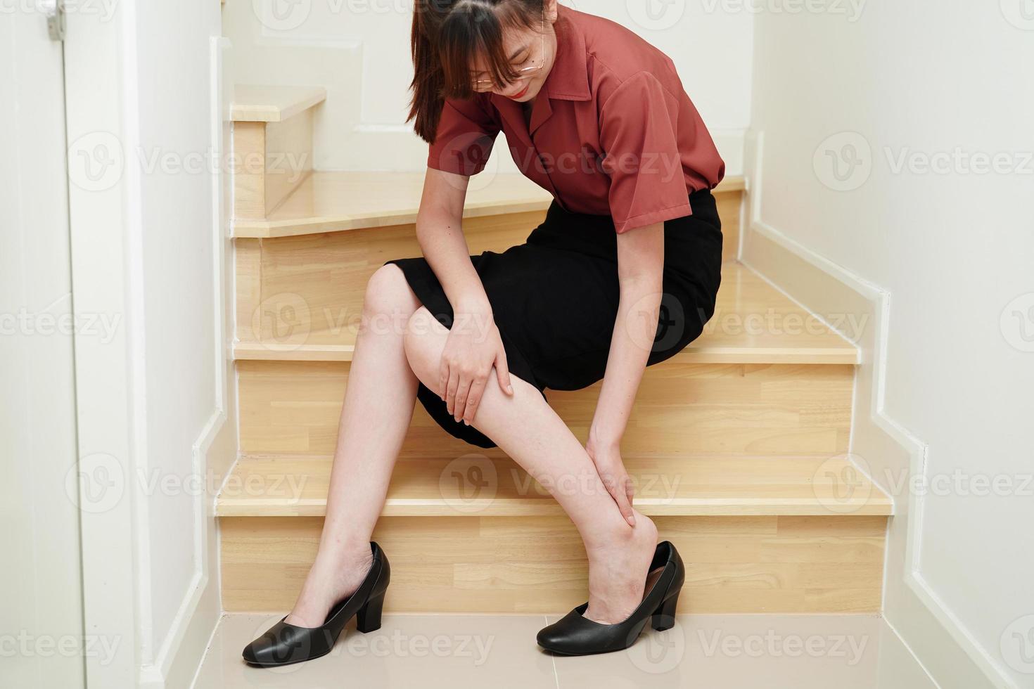 Asian business woman pain ankle, foot with leg cramp and fall down the stairs because slippery surfaces in office. photo