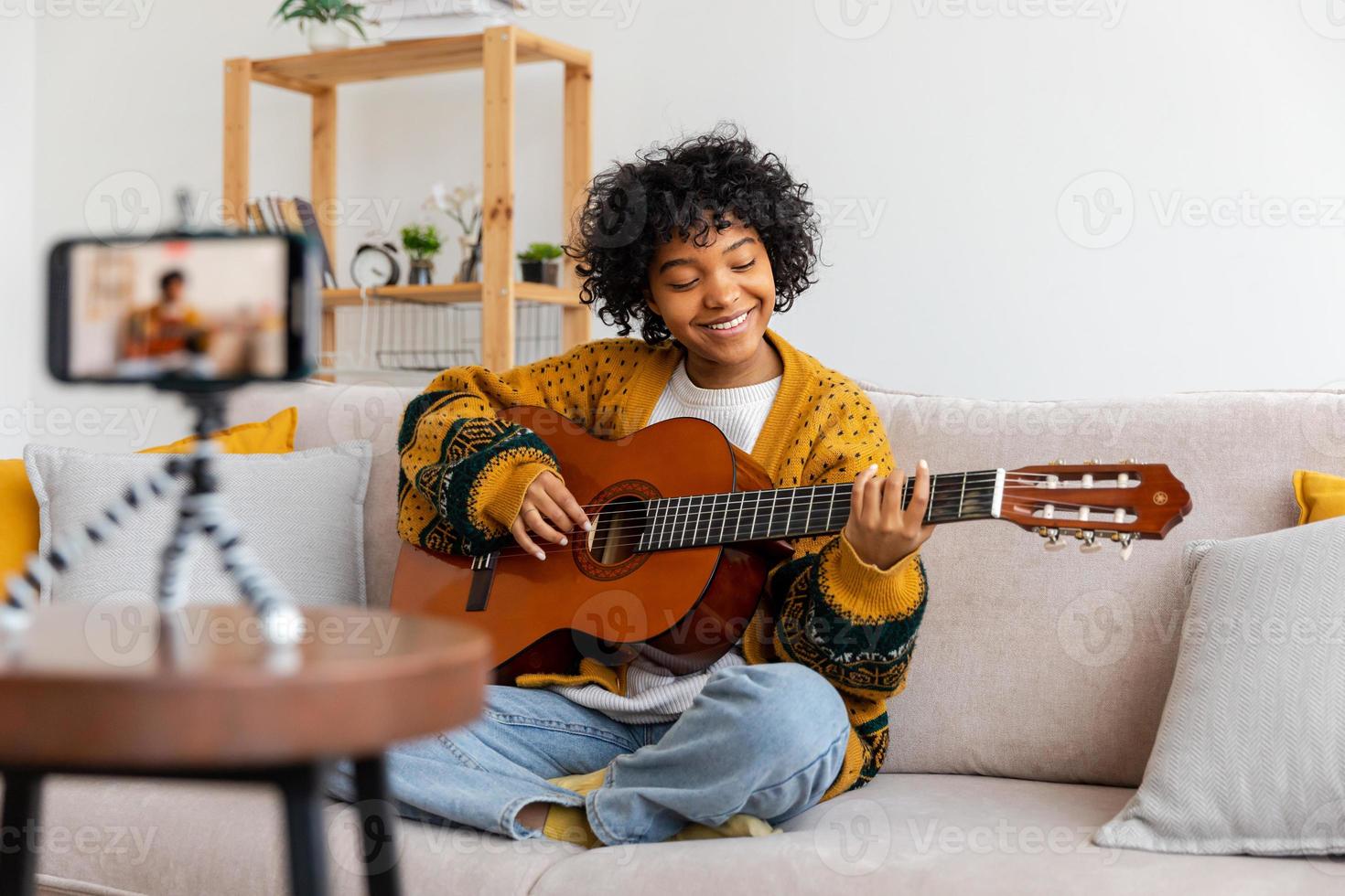 Blogger guitarist. Happy african american girl blogger playing guitar singing song recording vlog. Social media influencer woman streaming recording at home studio. Music content creator broadcast. photo