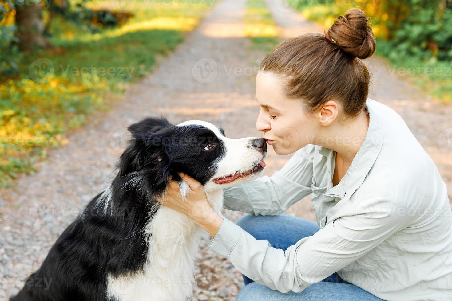 Smiling young attractive woman playing with cute puppy dog border