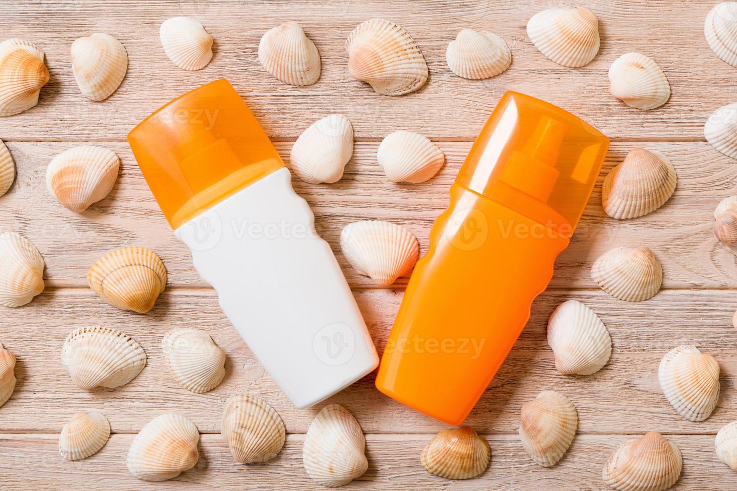 Top view of sunscreen bottle with seashells on wooden board background with copy space. flat lay concept of summer travel vacation photo