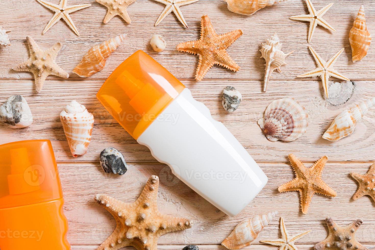 Top view of sunscreen bottle with seashells and starfish on wooden board background with copy space. flat lay concept of summer travel vacation photo