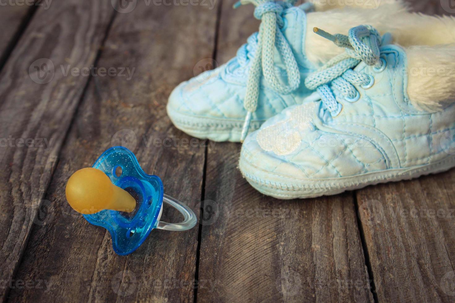 bebé Zapatos y un chupete en el antiguo de madera antecedentes. foto