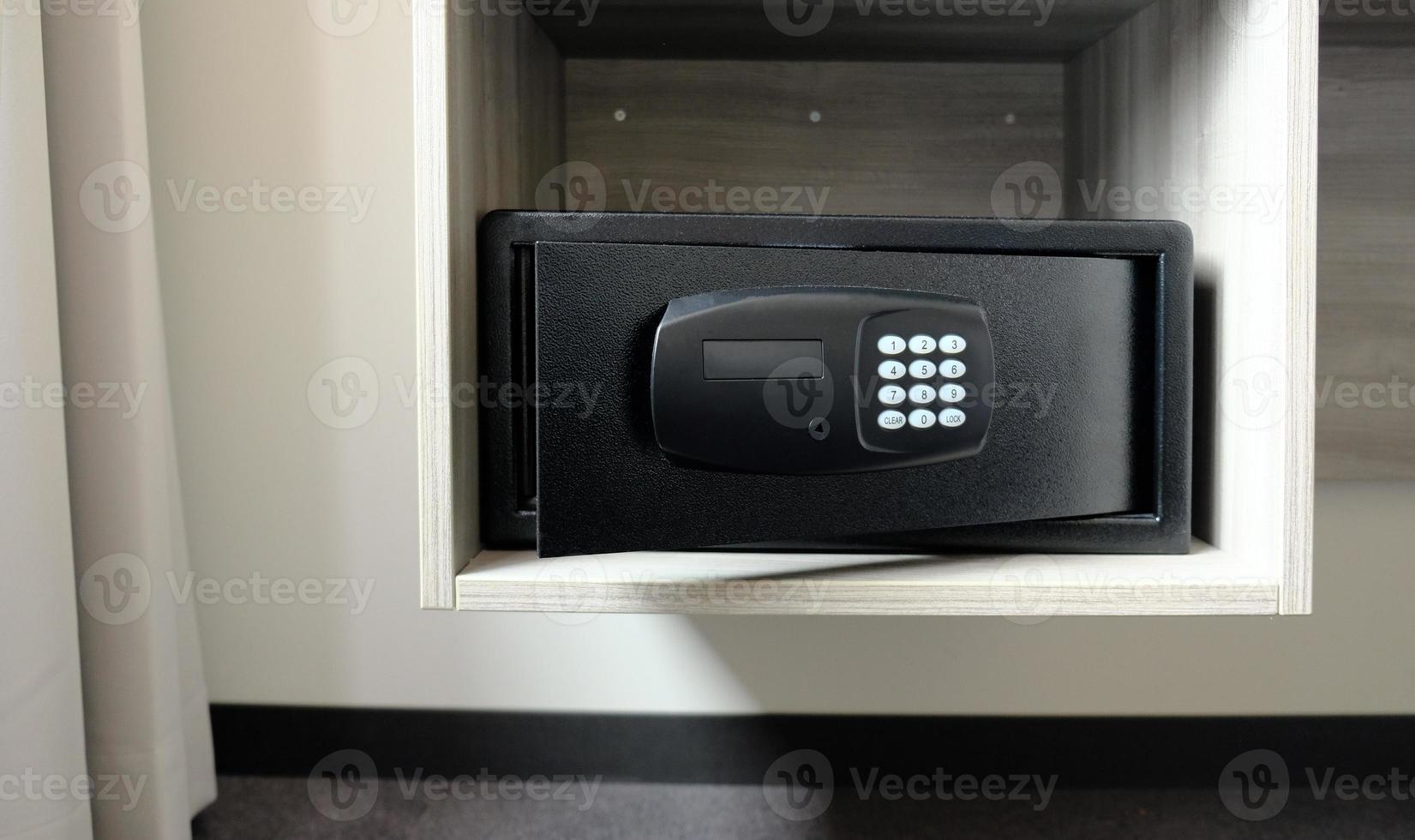 Metal safe box in the closet. Small narrow safe for keeping money or valuables in the hotel. Open safe door with buttons for entering a password. Compact strongbox inside cabinet. Empty safe. photo