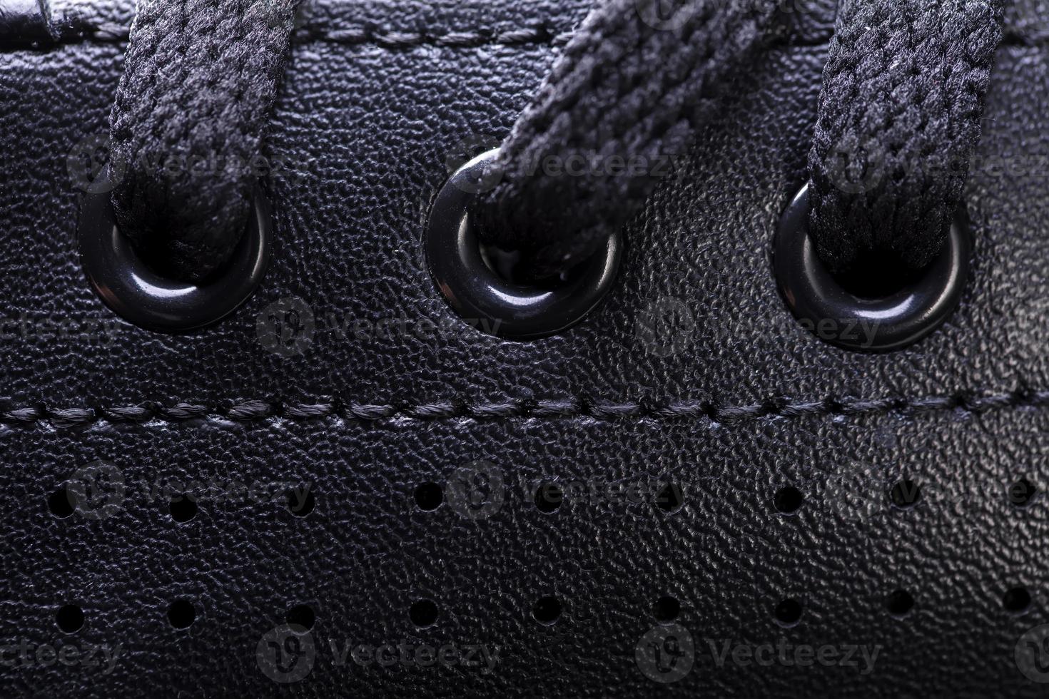 Part of a black boot with laces. A fragment of dark shoes. A piece of sneaker. photo