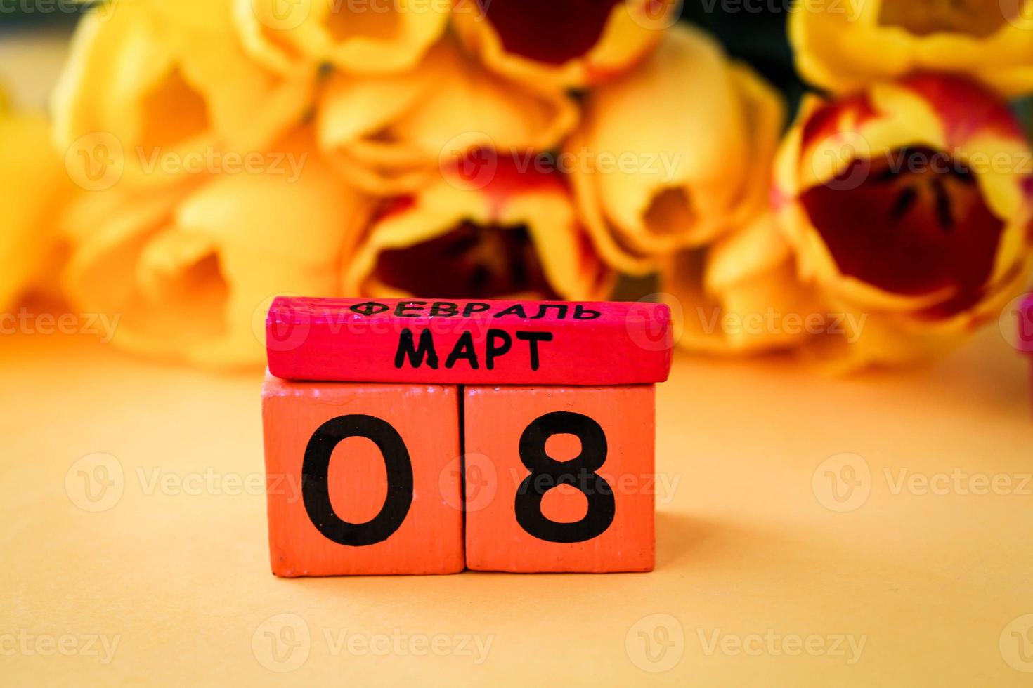 Wooden calendar with number 8 and  on a background of yellow tulips. Russian text March 8. International Women is Day 8 March. photo
