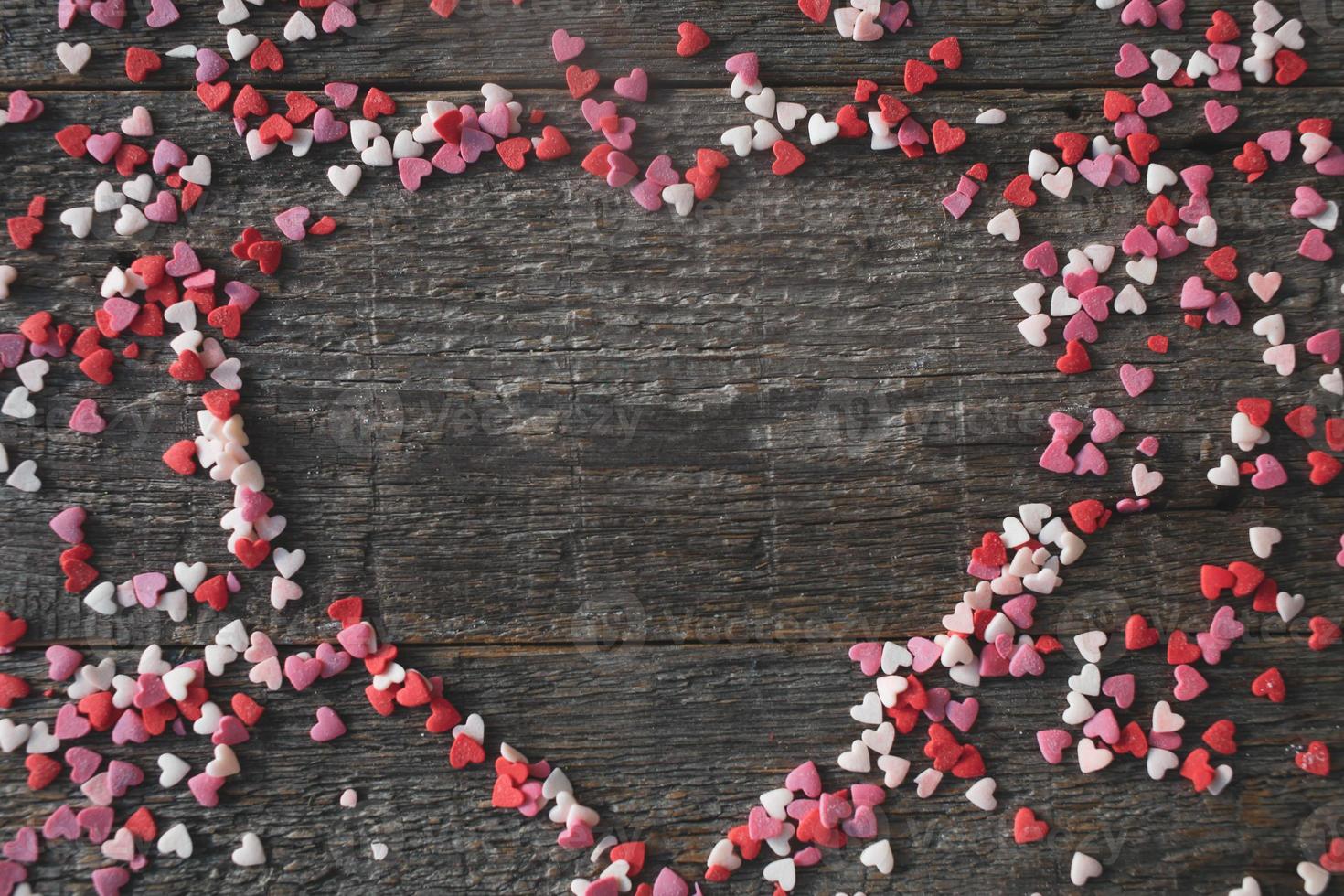 Sweet hearts in the shape of a heart on a wooden background. Frame in the heart of valentines day concept. photo