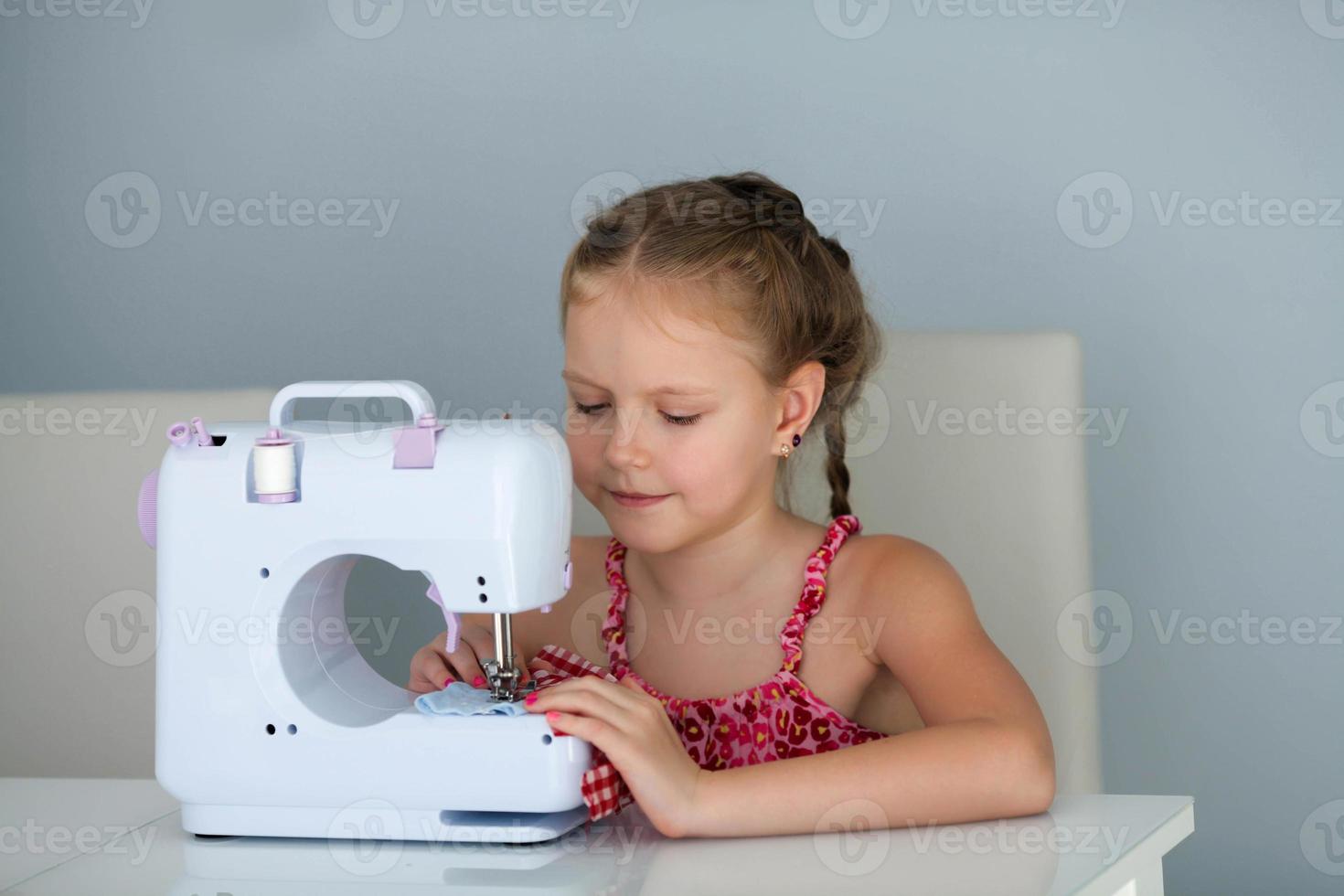 7 7 años antiguo niño estudiando trabajo con un moderno de coser máquina. foto