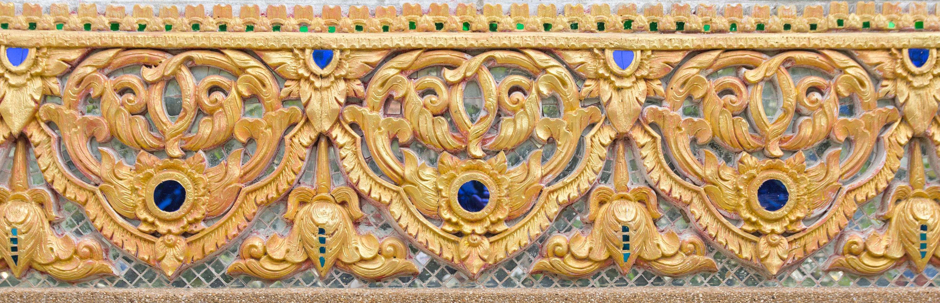 Pattern of gold flower carved on stucco design of native wall, Thai style in temple photo