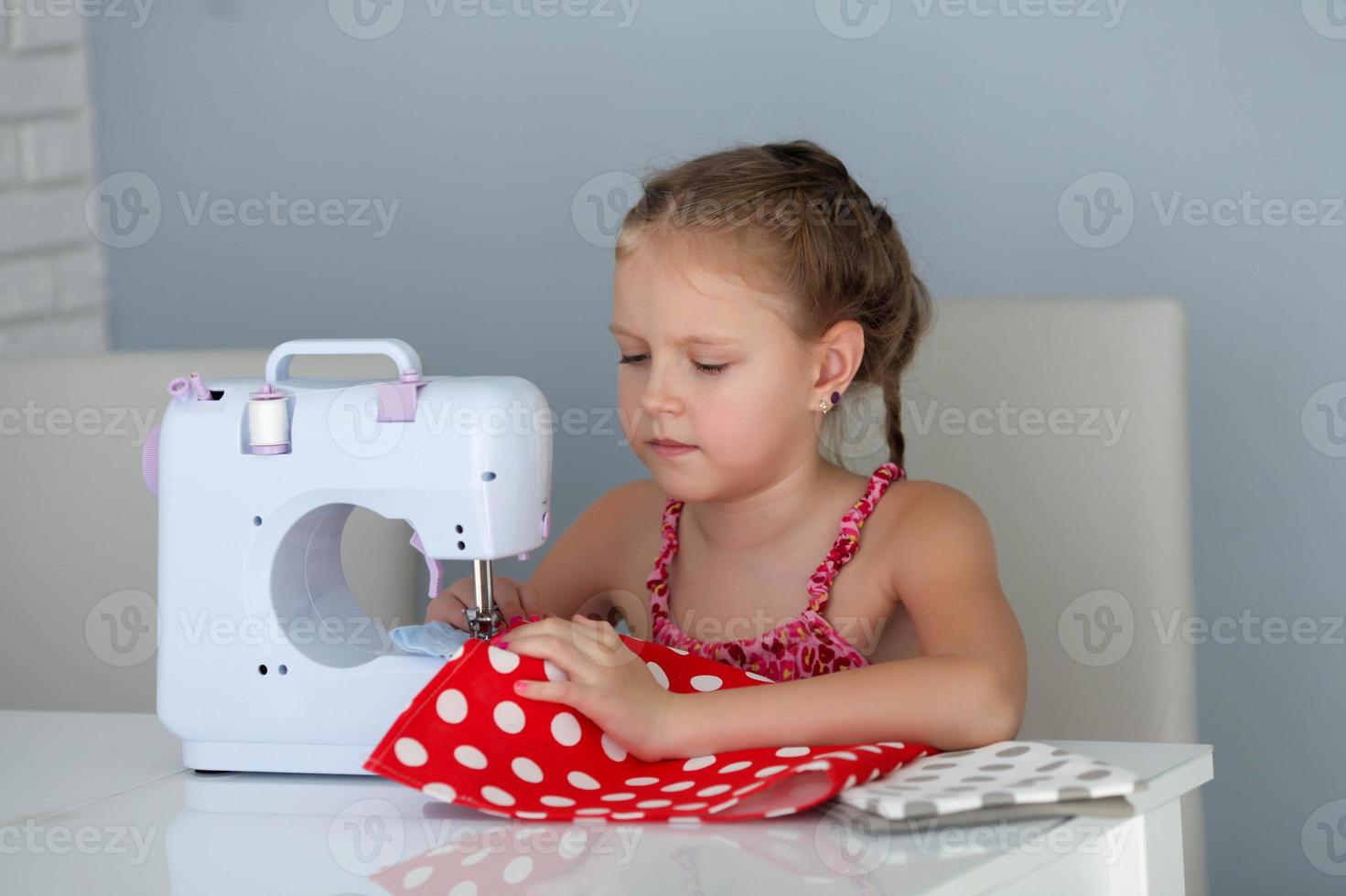 un hermoso, sonriente joven niña de coser en un un moderno de coser máquina. foto