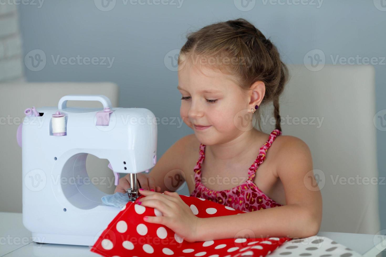 un hermoso, sonriente joven niña de coser en un un moderno de coser máquina. foto