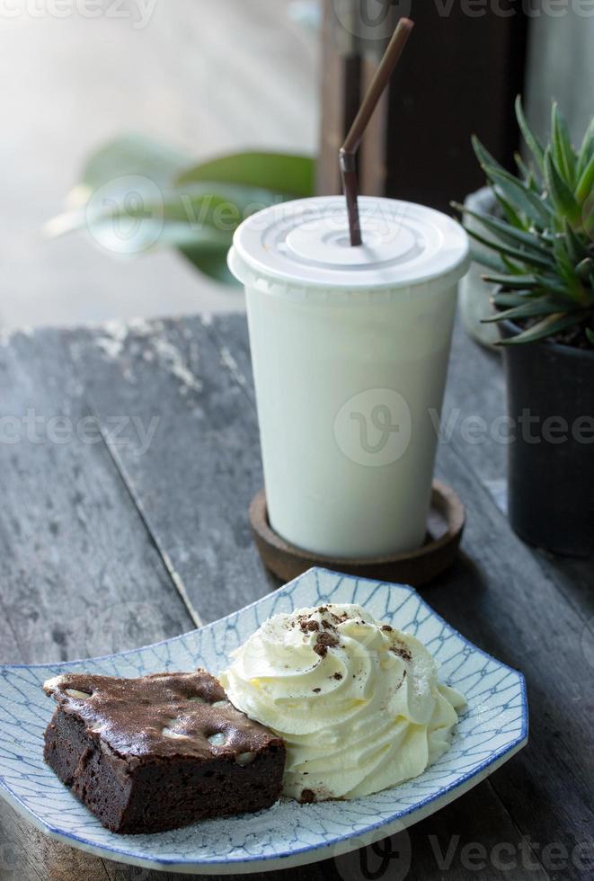 brownie cake with whipped cream and tea on the table photo