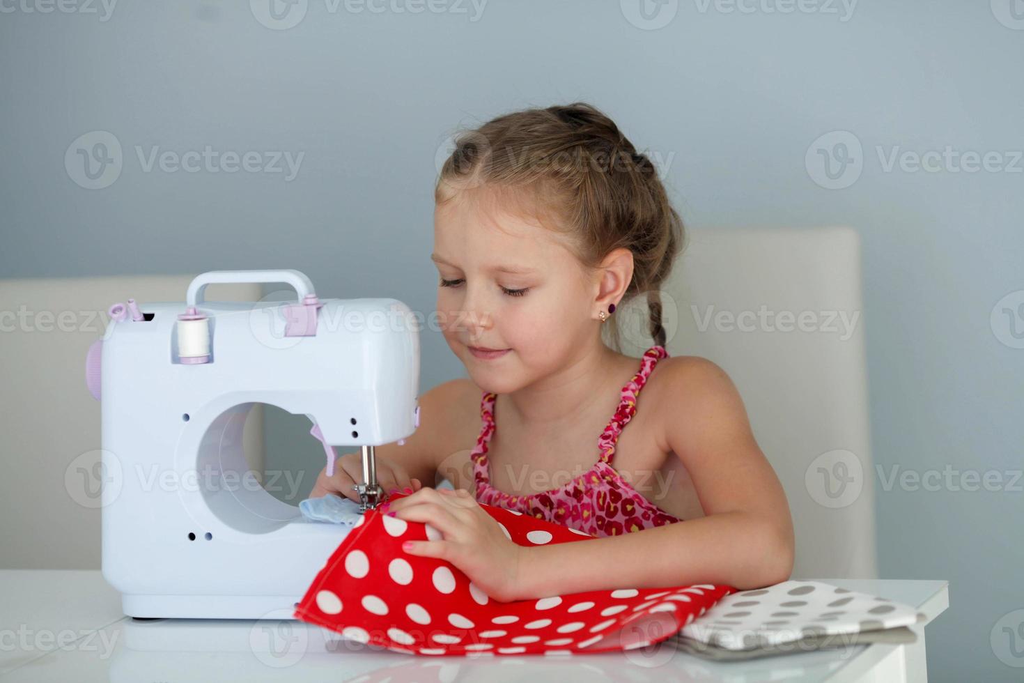 7 years old child studying work with a modern sewing machine. photo