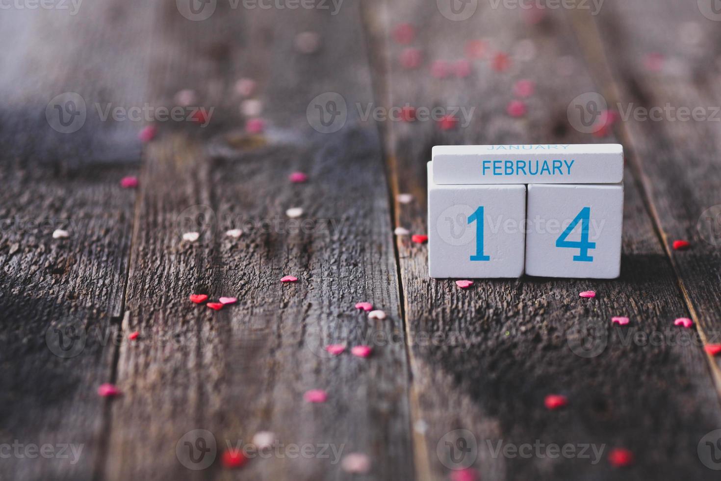 Date of February 14 on wooden calendar and pink hearts on wooden background. Valentines Day. photo