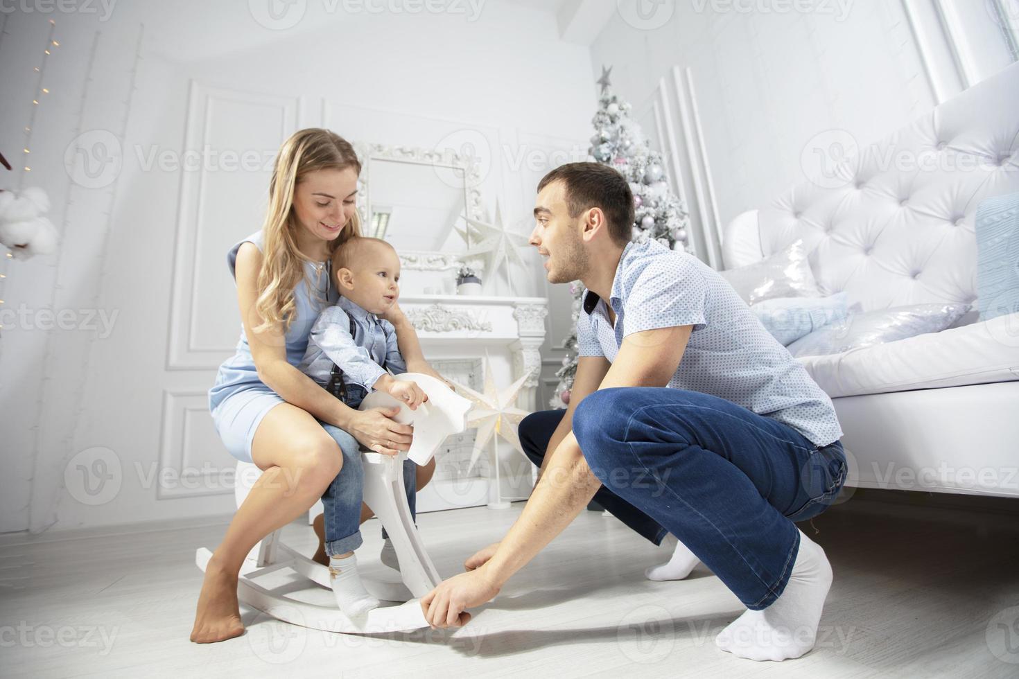 Family at Christmas. Mother father and child play against the background of a Christmas tree. Parents and son in the new year. photo