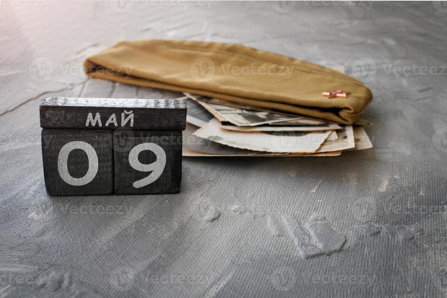 de madera calendario con ruso texto mayo 9 9 y guarnición gorra con antiguo fotos en un gris antecedentes. victoria día. Copiar espacio.