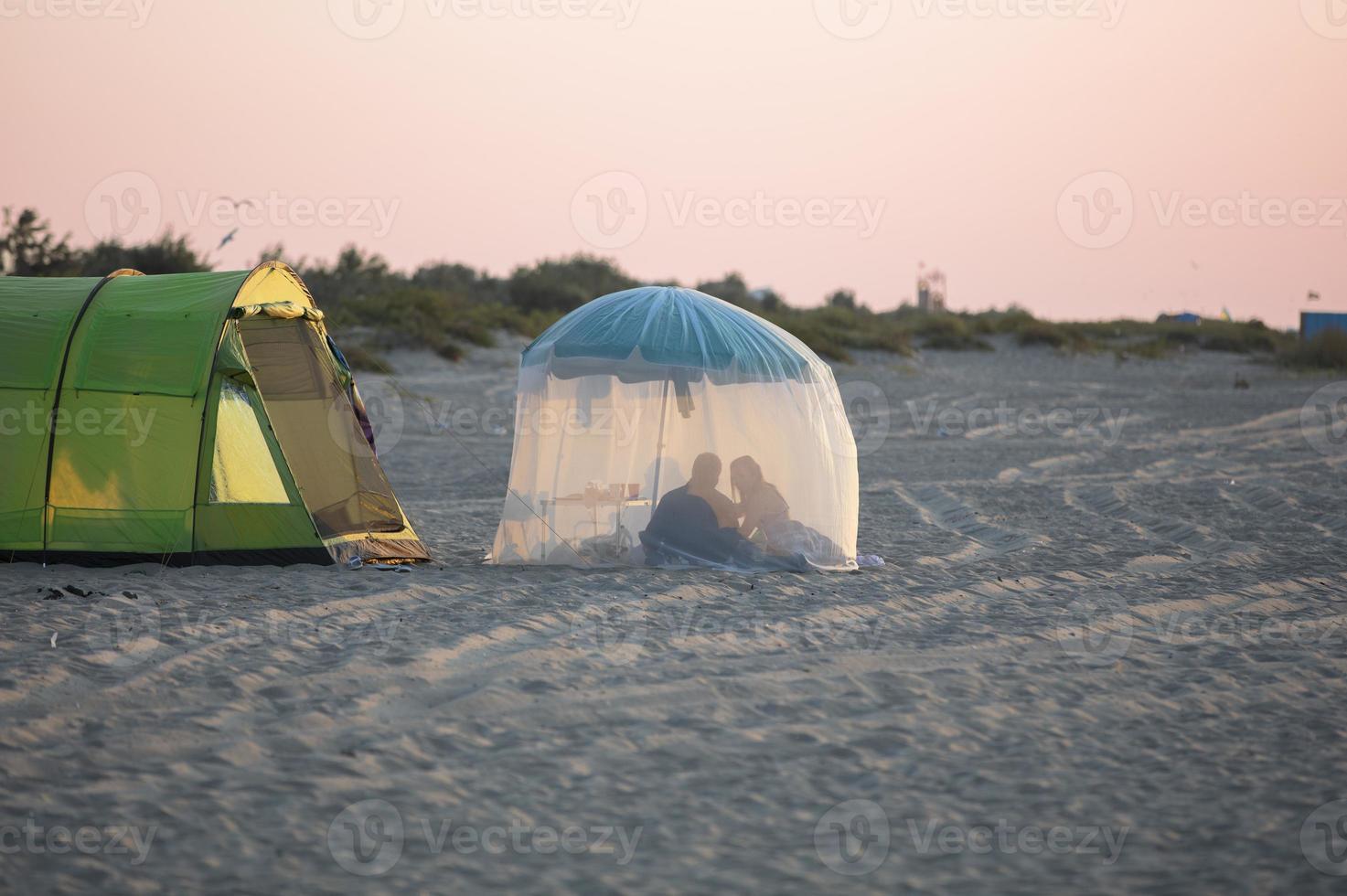 Relax on the beach in a tent. The coast and the silhouettes of people in the tent. photo