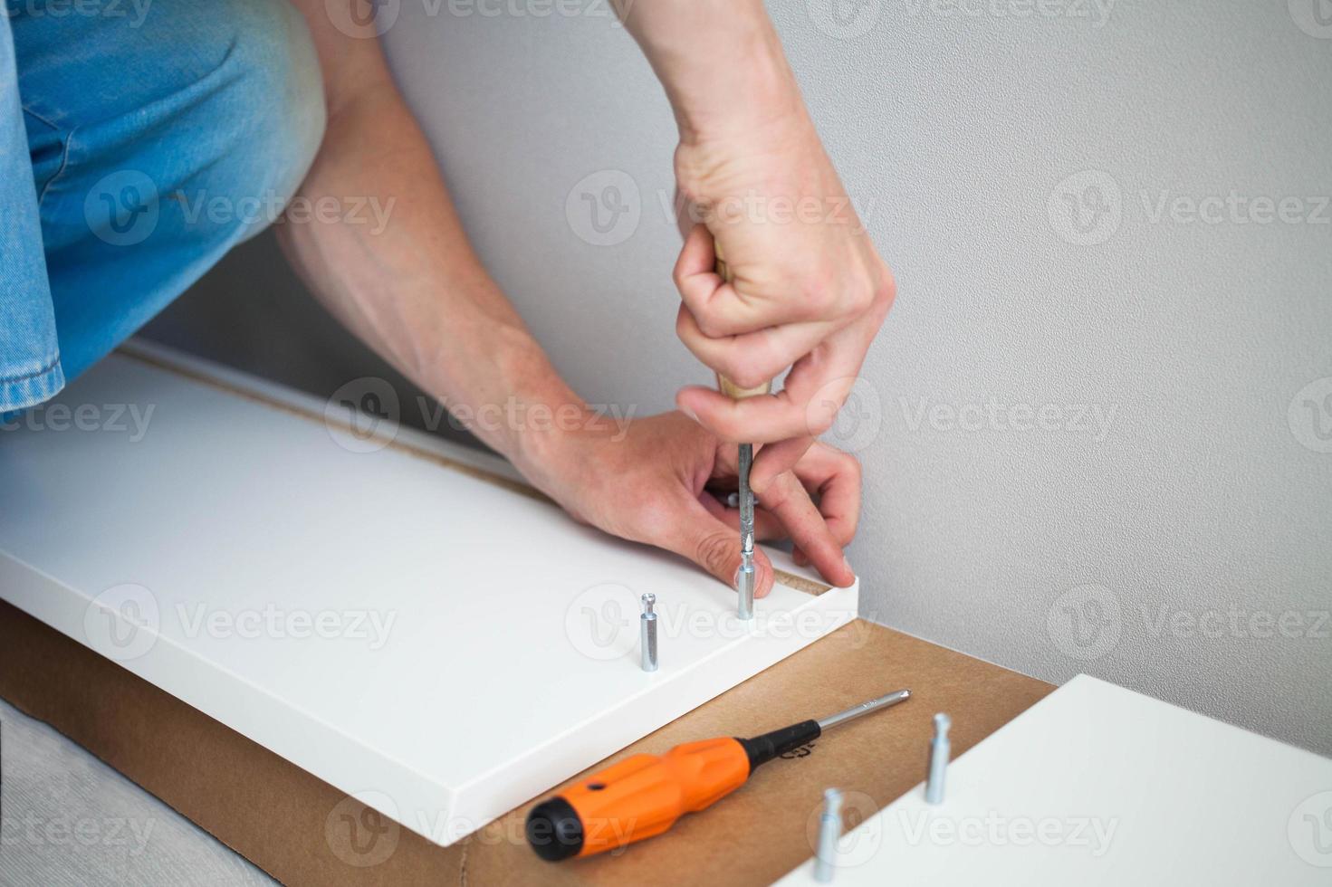 Close up of man hand, furniture assembler make flat  pack white furniture assembly service at home. photo