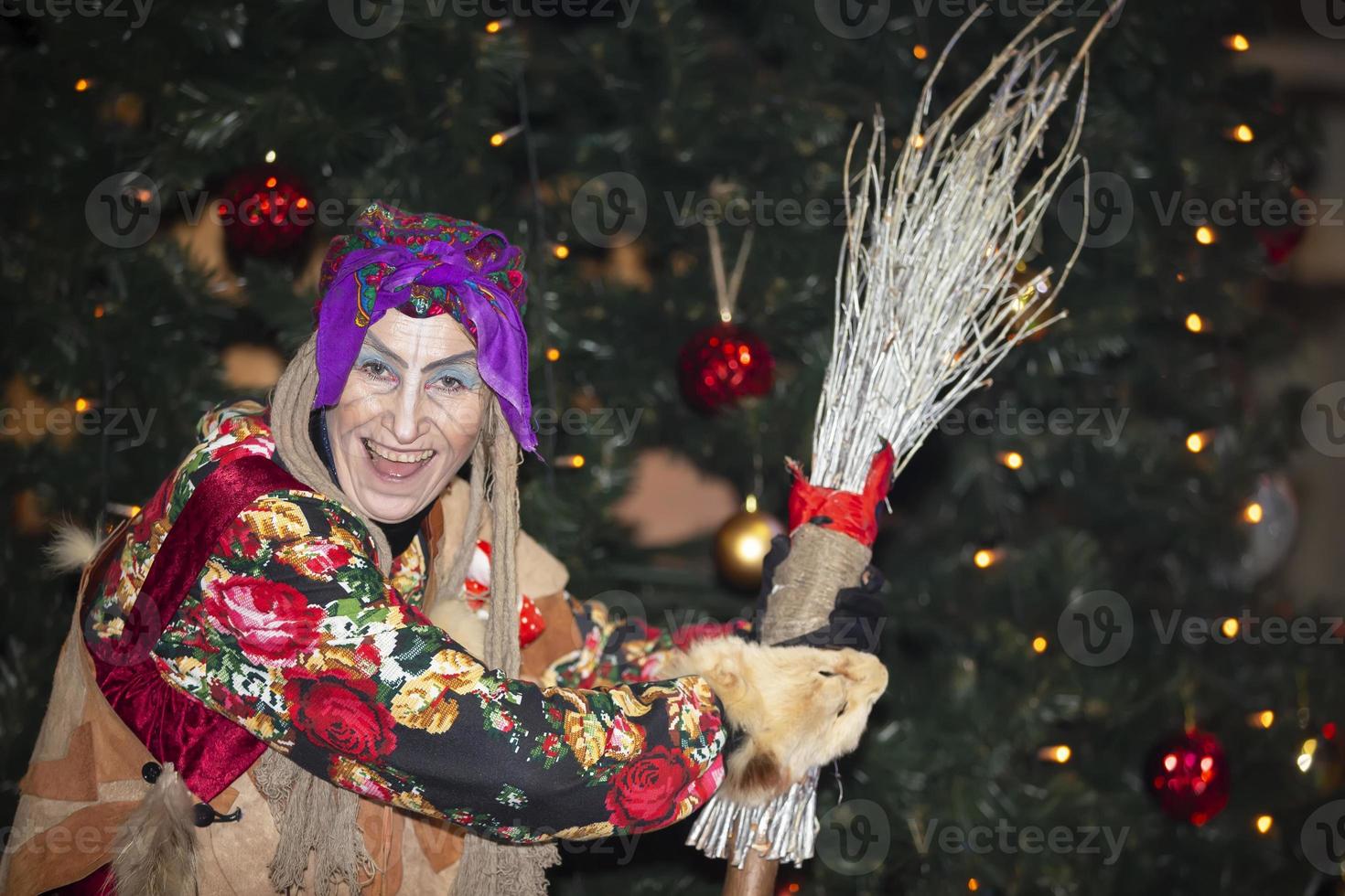 Baba Yaga with a broom on the background of the Christmas tree. photo