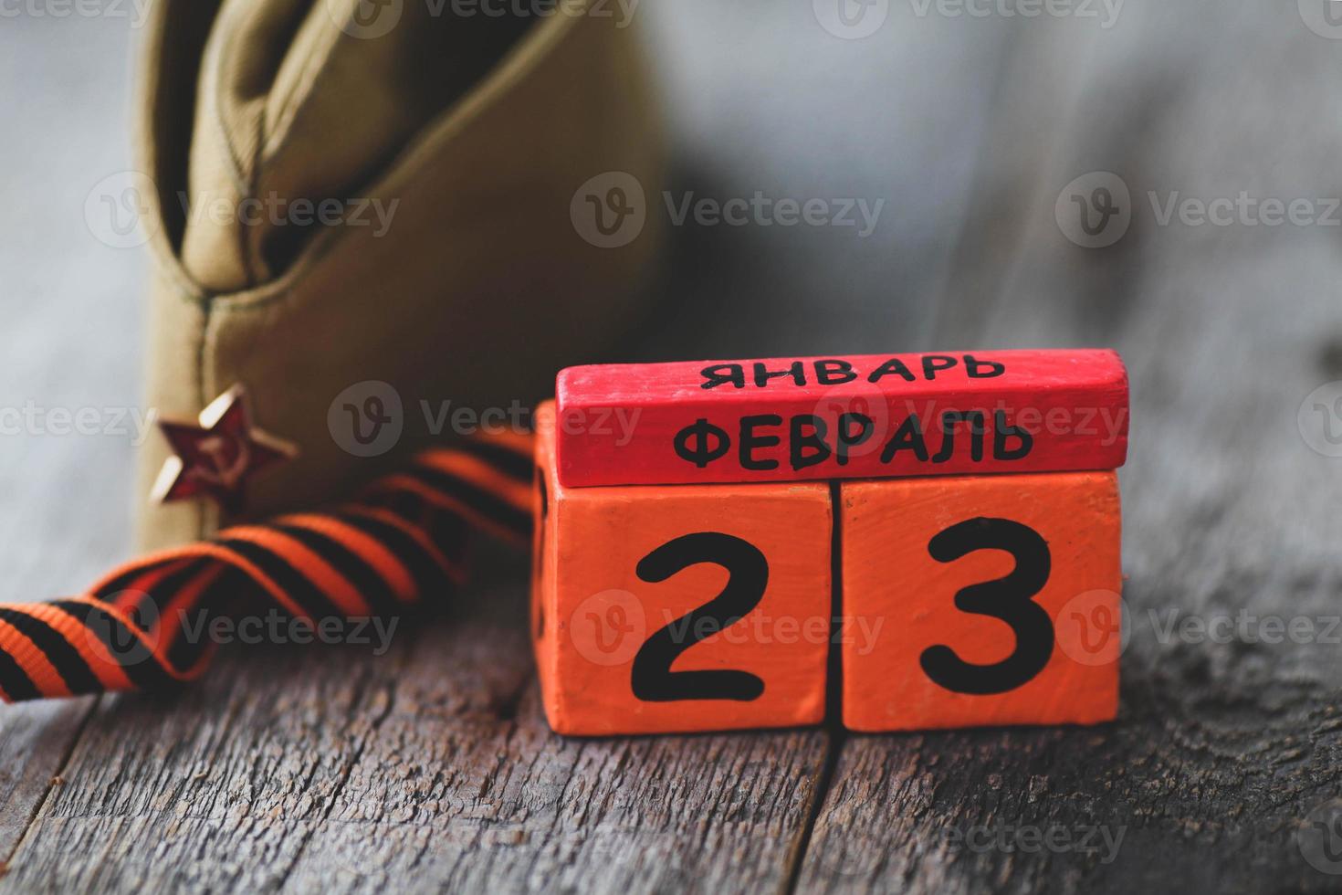 Wooden calendar with the date of February 23, St. George ribbon, garrison cap. Defender of the Fatherland Day. Men day in Russia, Belarus, Tajikistan. Text in Russian on February 23. photo