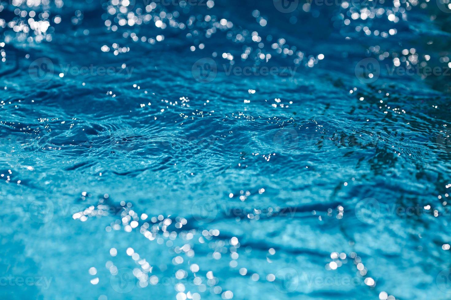Close-up of blue water in the pool. Side view. Bokeh light background in the pool. photo